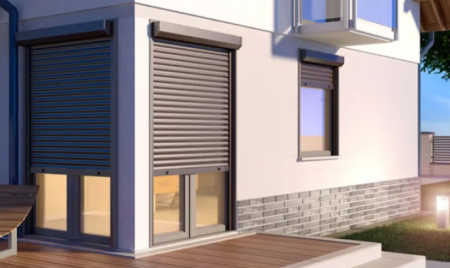 Motorised roller shutters closed over the windows of a modern home at dusk