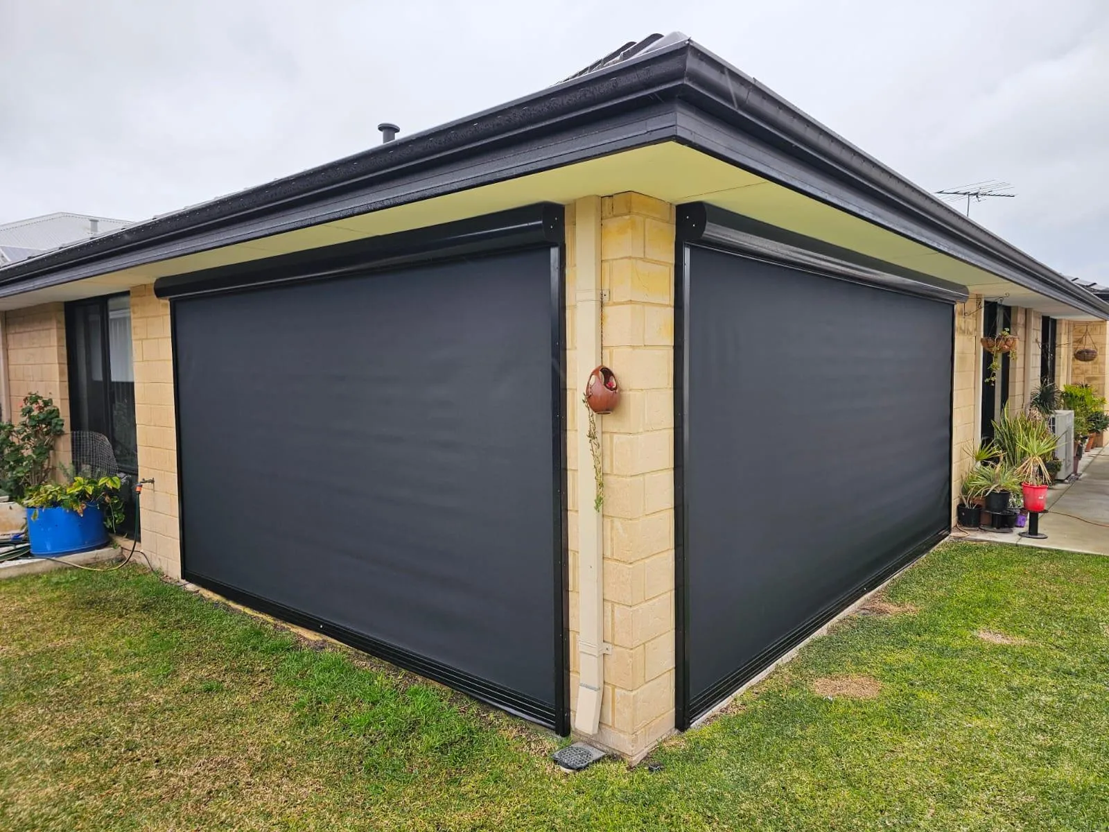 Black Slidetrack blinds wrapping the corner of a brick home’s alfresco