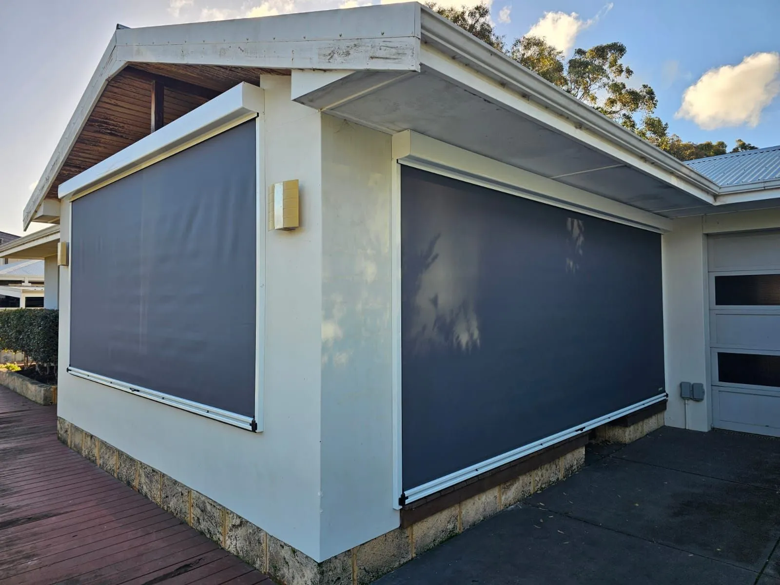 Charcoal Slidetrack blinds on the corner of a white rendered alfresco with a timber deck
