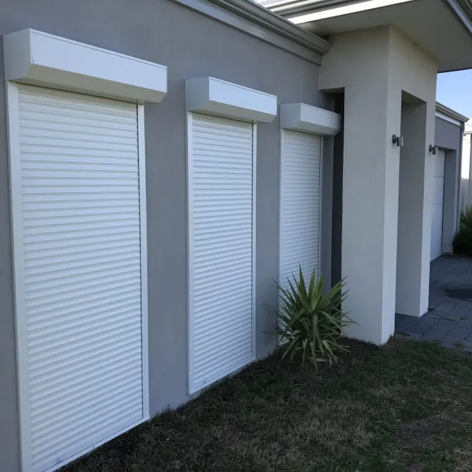 Three white roller shutters on a grey rendered Perth home